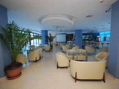 Przestronny, nowoczesny salon hotelowy z wygodnymi fotelami i roślinami.