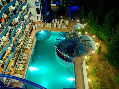 Beleuchteter Poolbereich mit Liegestühlen und rundem Barbereich im Hotel bei Nacht