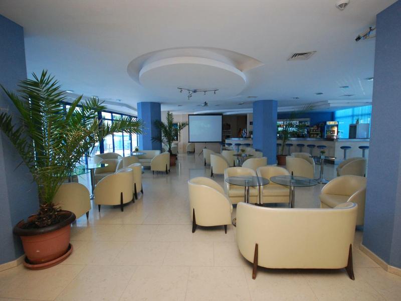 Przestronny, nowoczesny salon hotelowy z wygodnymi fotelami i roślinami.