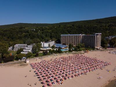 Plaża z czerwonymi parasolami i hotelami w tle na tle zalesionych wzgórz