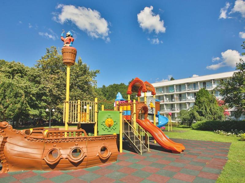 Plac zabaw na zewnątrz z łodzią piracką przed budynkiem hotelu pod niebieskim niebem