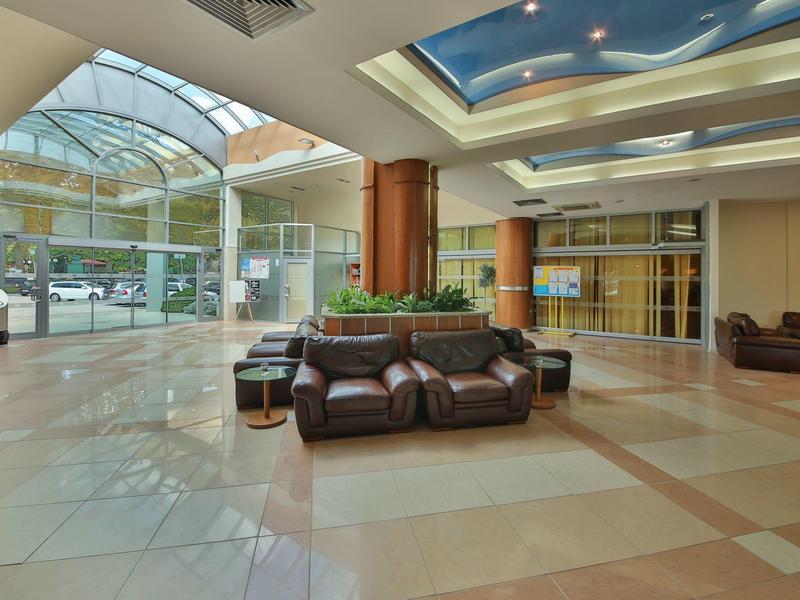 Jasny hol hotelowy z skórzanymi siedzeniami i szklaną kopułą