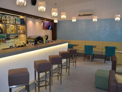 Moderní bar v hotelu s barovými židlemi a sedadly v jemných barvách.