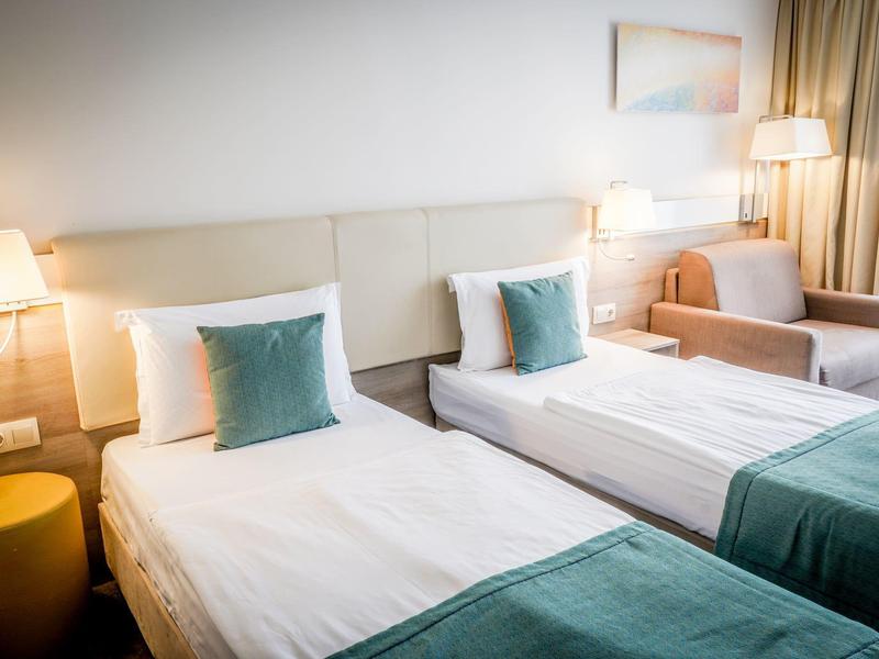 Dzieci śmieją się i tworzą przy stole z opiekunką w jasnym pomieszczeniu.