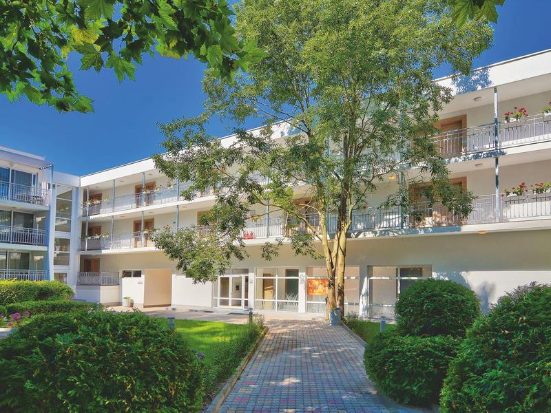 Nowoczesny kompleks hotelowy z ogrodem, drzewami i ścieżką w słoneczny dzień