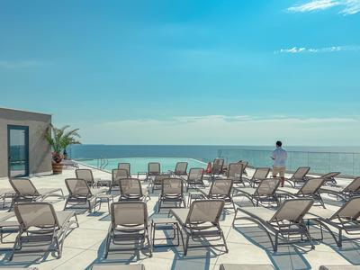 Sun terrace with lounge chairs and sea view under a blue sky.