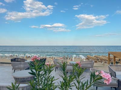 Nowoczesny balkon z miejscami do siedzenia i widokiem na morze pod błękitnym niebem.