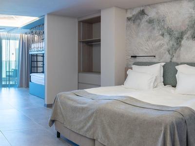 Nowoczesny pokój hotelowy z dużym łóżkiem, biurkiem i balkonem z widokiem na zewnątrz.