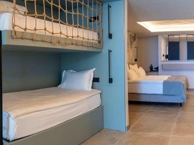 Nowoczesny pokój wieloosobowy z łóżkami piętrowymi, niebieską ścianą i minimalistycznym wystrojem.