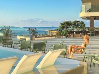 Kobieta relaksująca się przy basenie z widokiem na morze i taras hotelowy.