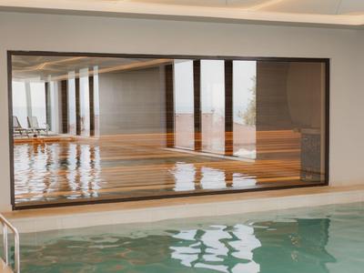 Widok na kryty basen z dużym oknem wychodzącym na przylegający drewniany podest.