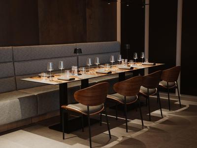 Elegancka jadalnia z drewnianymi stołami, nowoczesnymi krzesłami i przyciemnionym oświetleniem.