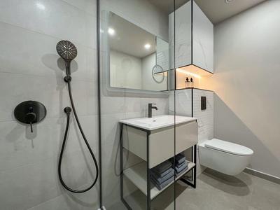 Nowoczesna łazienka hotelowa z prysznicem, umywalką i wiszącą toaletą w minimalistycznym stylu.