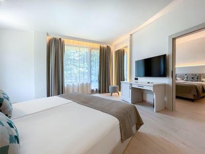 Nowoczesny pokój hotelowy z podwójnym łóżkiem, telewizorem płaskoekranowym i dużym oknem z zasłonami.