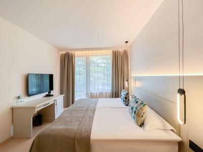 Nowoczesny pokój hotelowy z dwoma łóżkami, telewizorem i dużym oknem z zasłonami