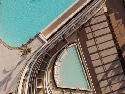 Widok z góry na dwa baseny i samotnego pływaka w hotelu.