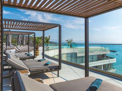 Modern terrace lounge with sunbeds and sea view on a sunny day.