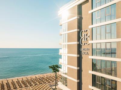 Modern hotel complex on the beach overlooking the sea in sunlight.