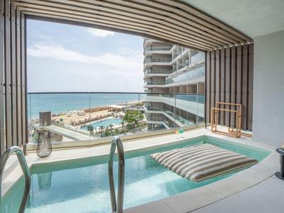 Balkon met klein zwembad, uitzicht op de zee en aangrenzend hotelgebouw