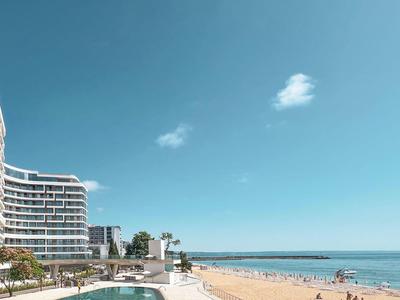 Wolnostojąca wanna przy dużym oknie z widokiem na morze i zasłonami.