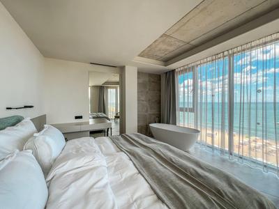 Nowoczesny pokój hotelowy z łóżkiem, wolnostojącą wanną i widokiem na morze przez duże okna