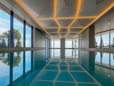 Nowoczesny basen kryty z dużymi oknami i stylowym oświetleniem sufitowym