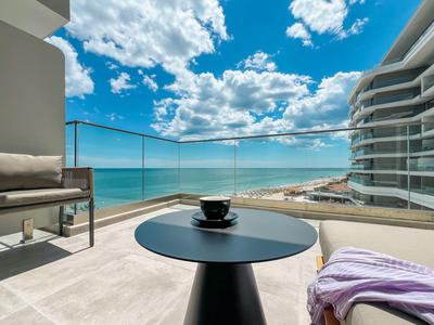 Balkon z widokiem na morze, stół z kubkiem i wygodnymi miejscami do siedzenia