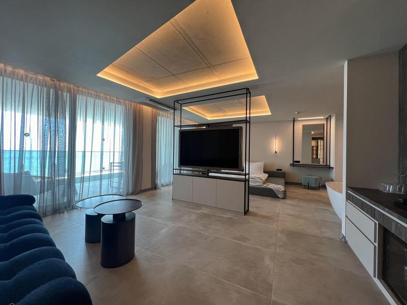 Nowoczesny pokój hotelowy z dużym oknem, oświetleniem sufitowym LED i stylowym wyposażeniem.