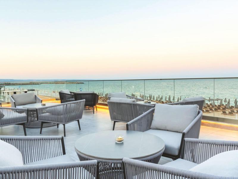 Taras z nowoczesnymi krzesłami i stołami z widokiem na morze o zachodzie słońca