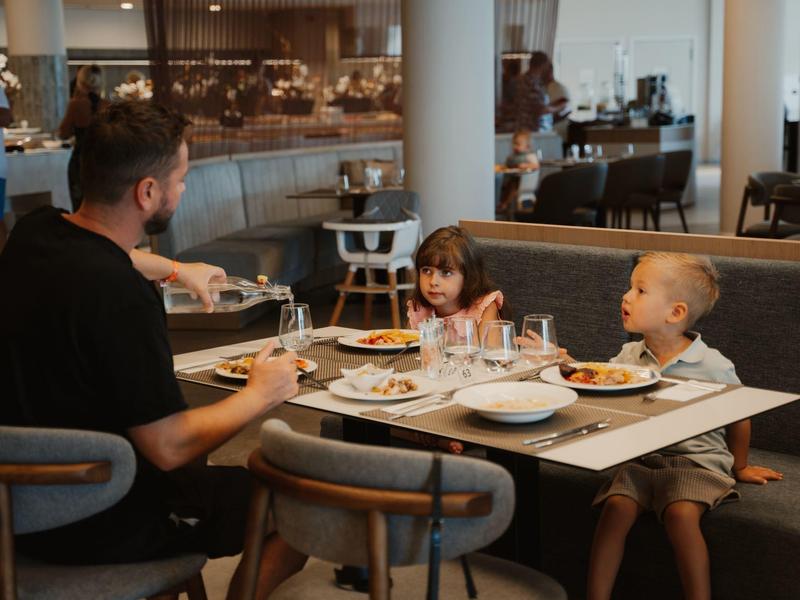 Mężczyzna je z dwojgiem dzieci przy stole w restauracji.