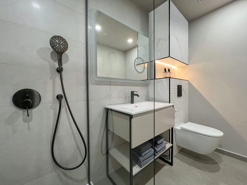 Nowoczesna łazienka hotelowa z prysznicem, umywalką i wiszącą toaletą w minimalistycznym stylu.