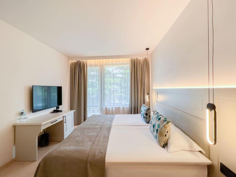 Nowoczesny pokój hotelowy z dwoma łóżkami, telewizorem i dużym oknem z zasłonami