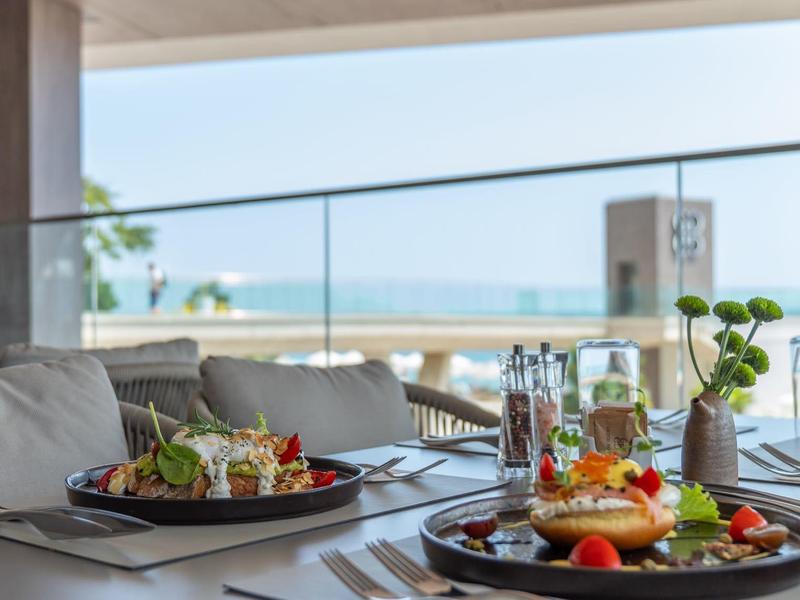 Stół w restauracji z widokiem na morze i podanymi daniami śniadaniowymi.