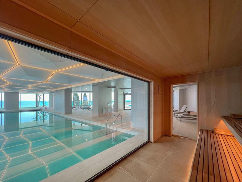 Wnętrze nowoczesnego basenu krytego z dużymi oknami i drewnianą boazerią.