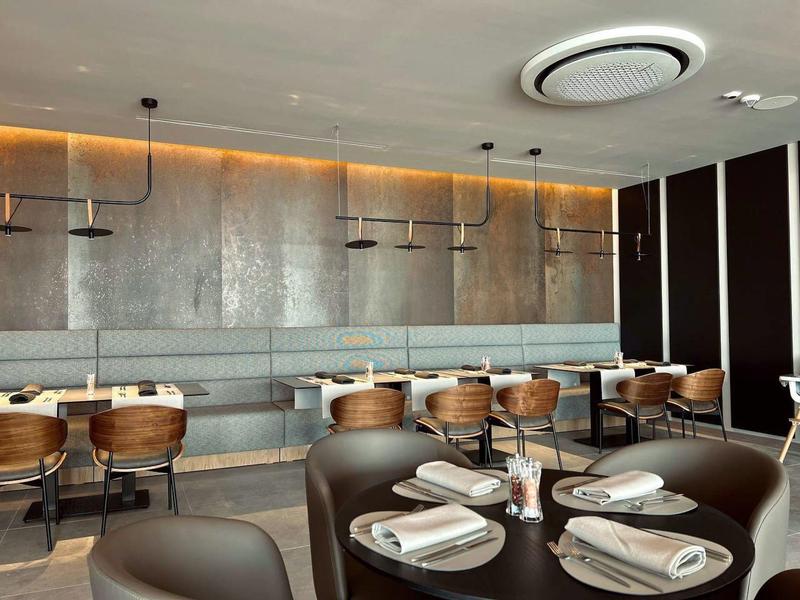 Nowoczesna jadalnia z nakrytymi stołami i drewnianymi krzesłami w eleganckim hotelu.