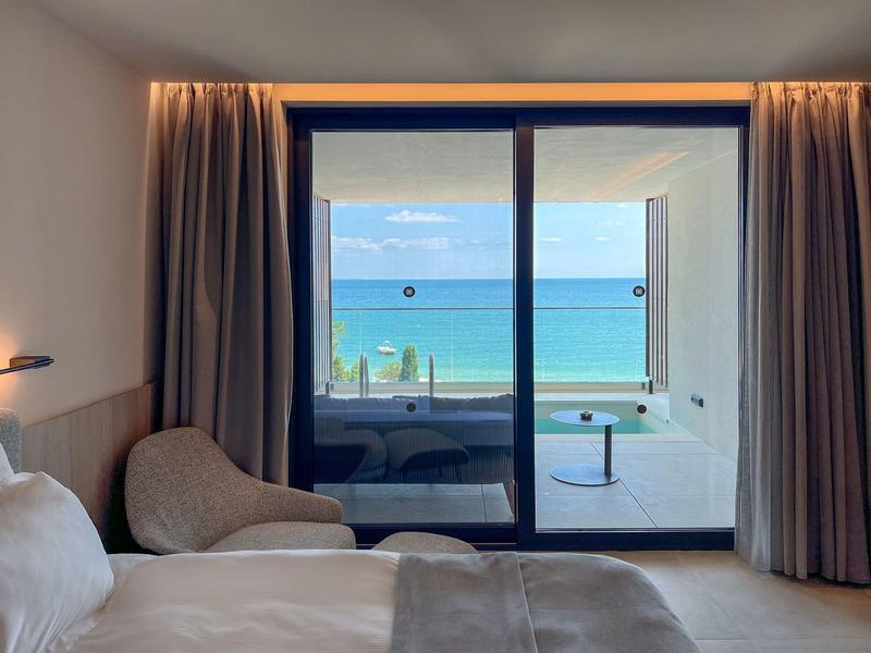 Widok na horyzont morza z pokoju hotelowego z balkonem i miejscem do siedzenia.