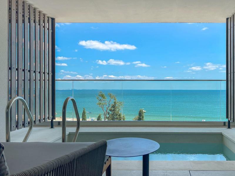 Widok na morze z nowoczesnego tarasu z basenem i miejscem do siedzenia.