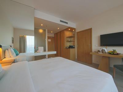 Modernes Hotelzimmer mit Doppelbett, TV, Schreibtisch und hellem, schlichtem Design.