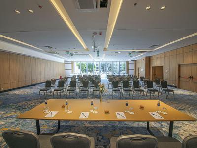 Großer Konferenzraum mit Stuhlreihen, Holzverkleidung und beleuchtetem Deckendesign.