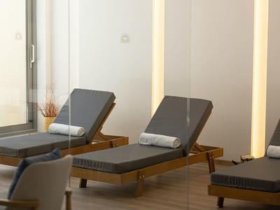 Drei graue Liegestühle mit Rollen und hellgrauen Kissen stehen in einem hellen, modernen Raum.