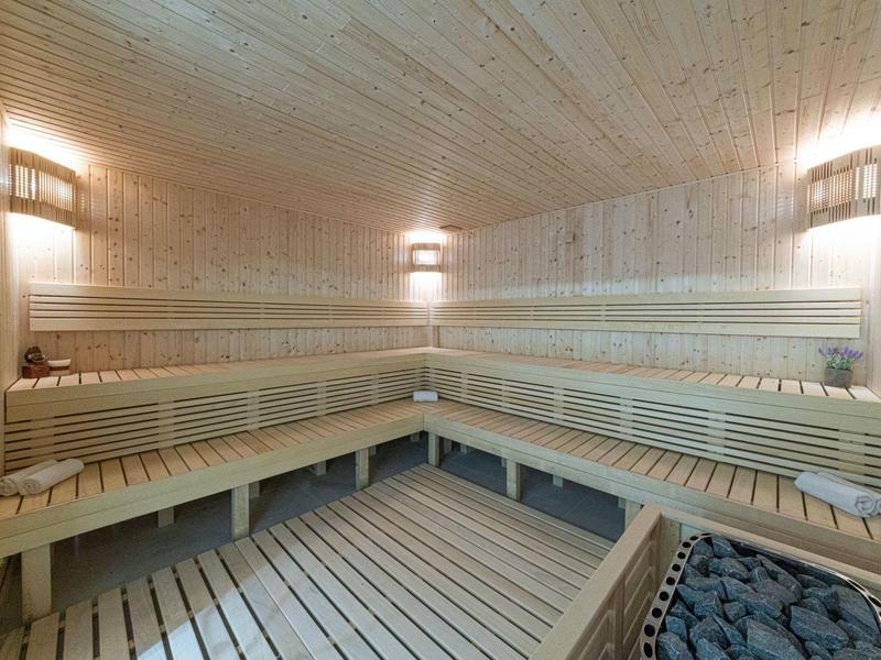 Große helle Sauna mit mehrstufigen Holzliegen und gedämpftem Wandlicht.