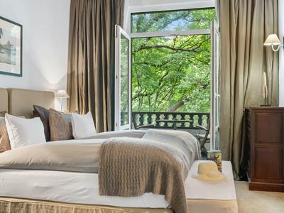 Camera d'hotel accogliente con letto grande e finestra aperta che dà su alberi verdi.