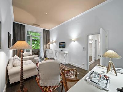 Soggiorno luminoso e arredato con stile con divano, tappeto e scrivania in una camera d'hotel.