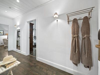 Corridoio d'hotel con appendiabiti, due accappatoi, sgabello con cappello e vista sulle stanze adiacenti.