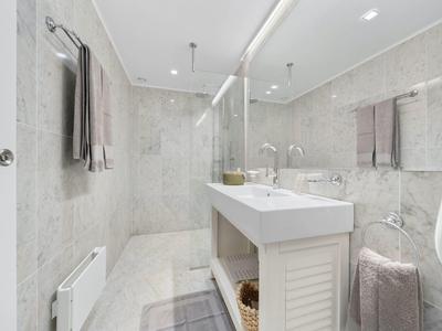 Bagno moderno con grande specchio, lavandini bianchi e asciugamani grigi.