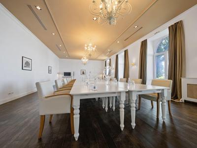 Elegante sala da pranzo con tavoli bianchi, sedie, lampadari e abbondante luce naturale.