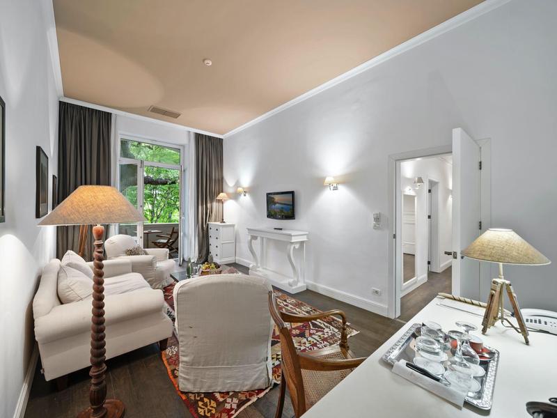 Soggiorno luminoso e arredato con stile con divano, tappeto e scrivania in una camera d'hotel.