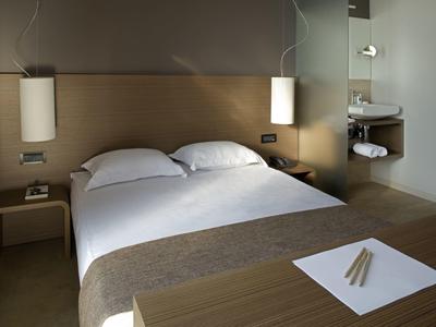 Nowoczesny, przytulny pokój hotelowy z podwójnym łóżkiem, lampami wiszącymi i prostym wystrojem.