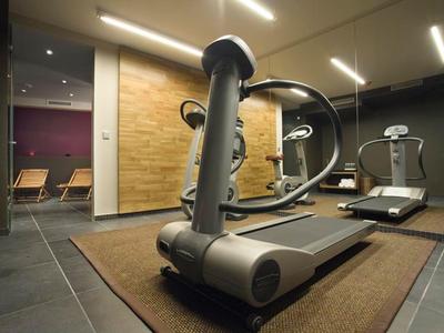 Salle de sport d'hôtel avec tapis roulants, miroirs et chaises longues.