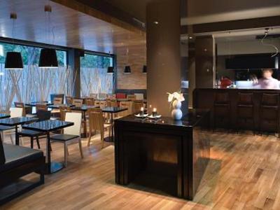 Nowoczesna restauracja z drewnianą podłogą i dużymi oknami, stylowo urządzona.